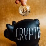 person putting bitcoin in a piggy bank
