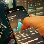 hand holding smartphone with cryptocurrency chart