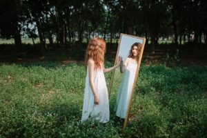 a woman in a red dress looking at herself in a mirror