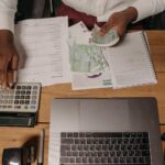 man sitting at the desk and counting money while using a calculator