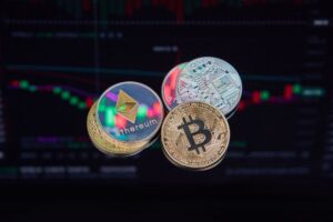 coins with cryptocurrencies symbols on the background of graphs