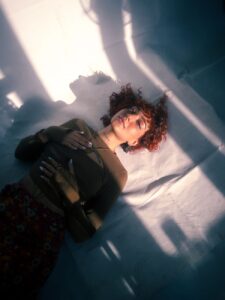 a woman laying on a bed with her head in the sun