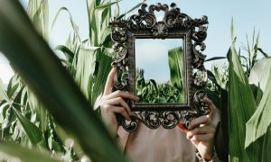 woman holding an ornamented retro mirror in a maize field