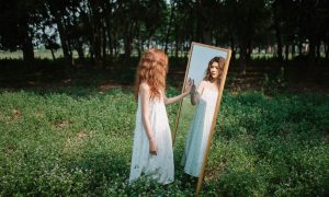 a woman in a red dress looking at herself in a mirror