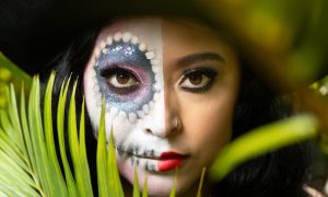 a woman with a skull face paint and a hat