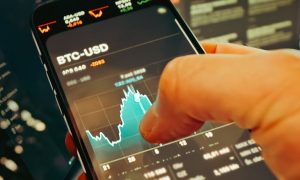 hand holding smartphone with cryptocurrency chart