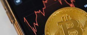 close up of a bitcoin coin lying on a screen displaying a stock market chart