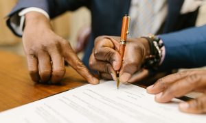 close up shot of a person writing on a contract