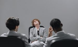 man looking up while sitting with his arms crossed